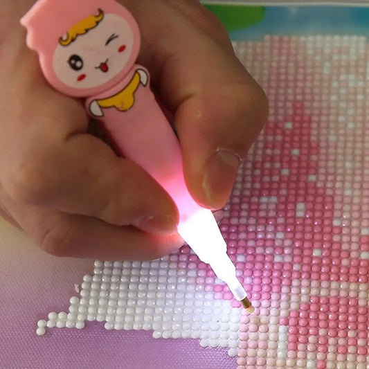 Using a pink LED cartoon crafting pen for diamond painting to apply crystals in low light; a fun and precise diamond art tool for enhanced visibility