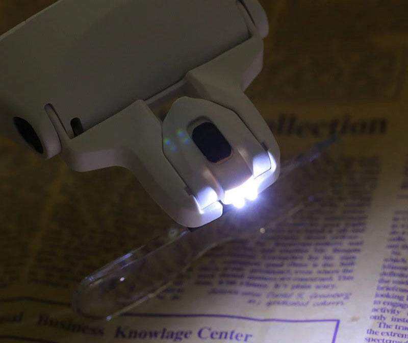 Small white light on a stand illuminating text on a newspaper