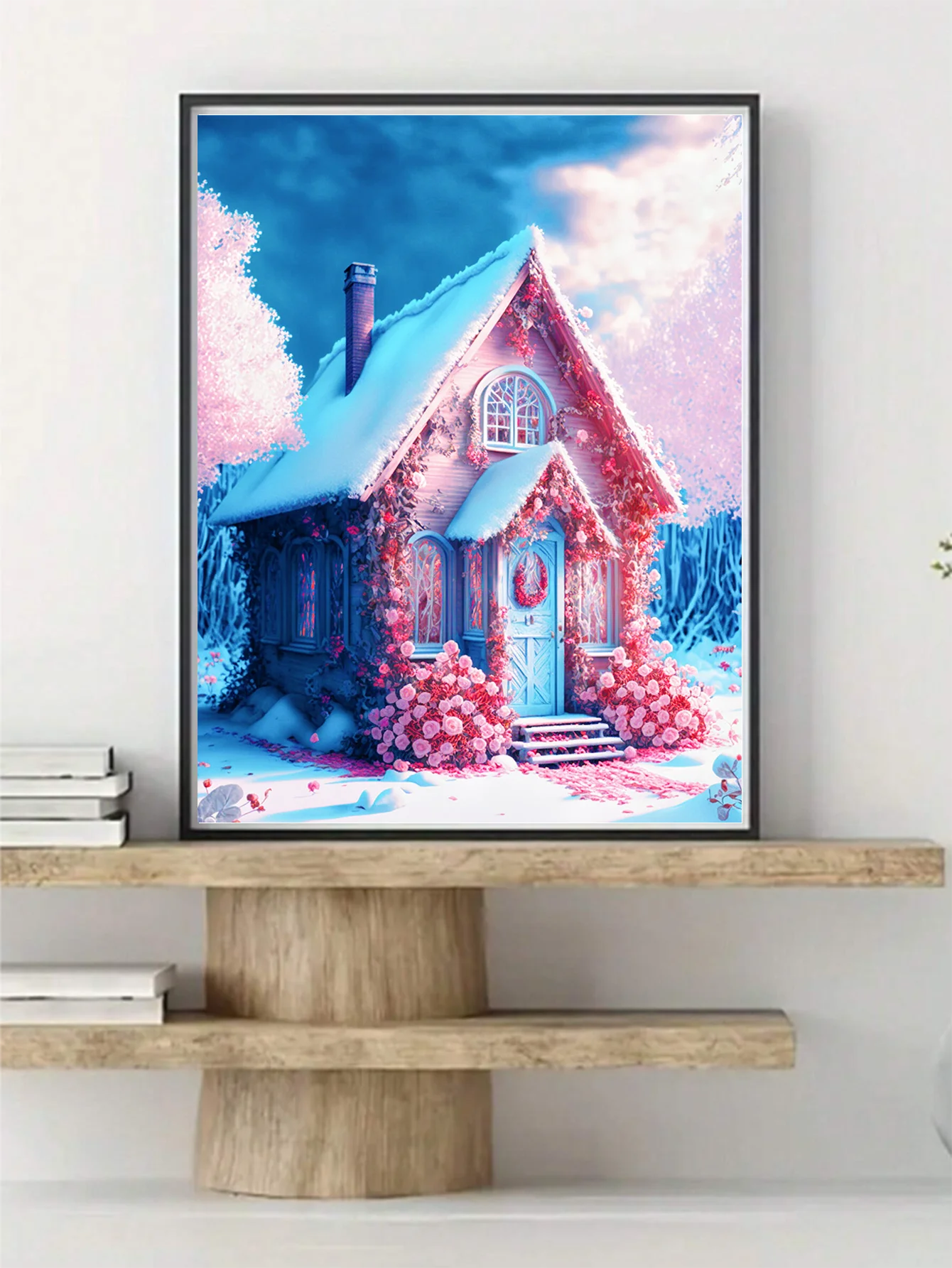 a quaint pink colored cottage surrounded  beautiful pink flowers. An intricate and yet delicate diamond painting masterpiece in a simple frame on a shelf